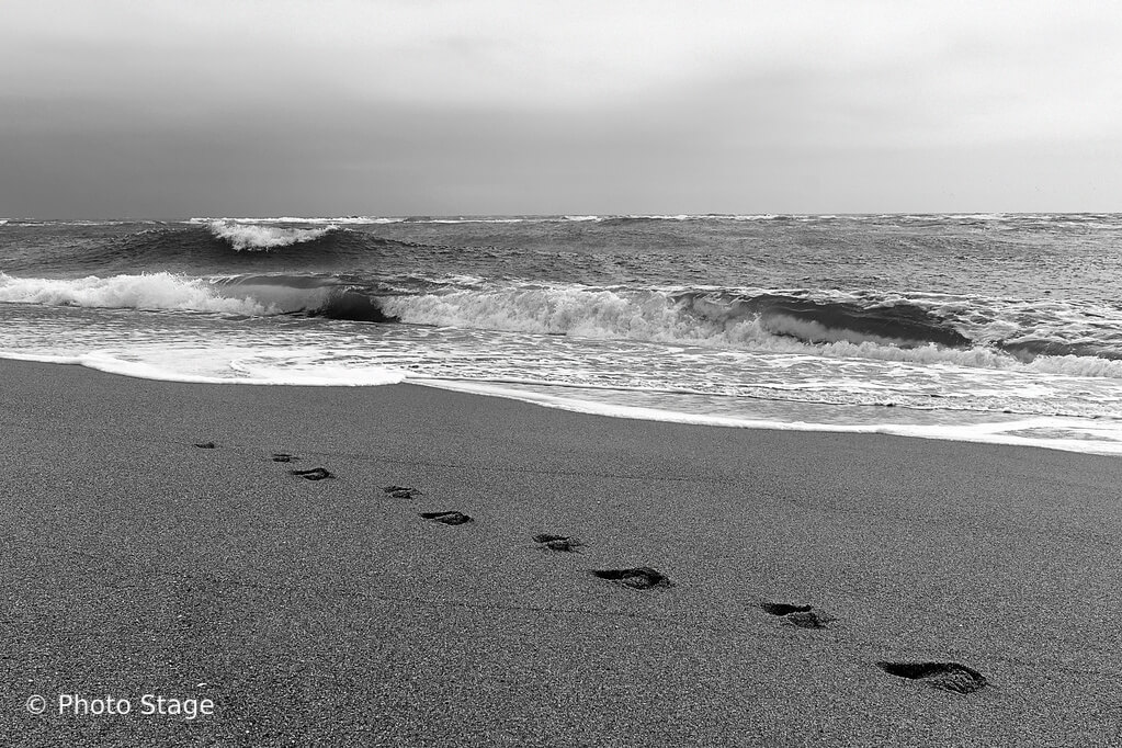 Une empreinte de pas sur le sable, près des vagues de l'océan atlantique